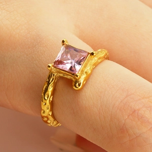 Hammered gold stainless steel ring with pink gemstone on model hand in close-up shot