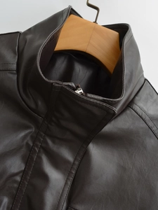 Detail of dark brown faux leather jacket with stand collar and zipper on wooden hanger