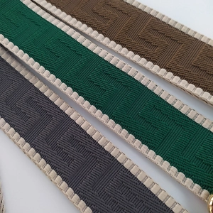 Detail of adjustable wide fabric bag straps with Greek key patterns in grey, green, and brown