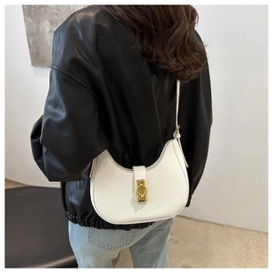 Dettaglio della borsa hobo bianca con fibbia dorata su una giacca di pelle nera chic