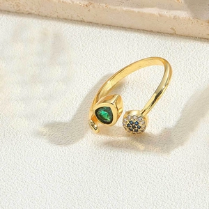 Detail of 14K gold open ring with green heart gem and blue zircon flower accents