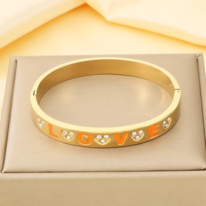 Detail view of gold 18K plated stainless steel bracelet with orange LOVE lettering and rhinestones