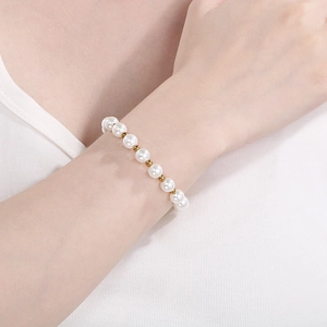 Detail shot of white freshwater pearl bracelet with gold metal beads on wrist