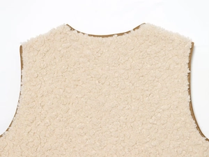 Close-up of cream faux shearling texture with brown leather piping detail on the vest