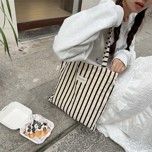 Detailed close-up of striped canvas tote bag fabric and branded label in outdoor setting