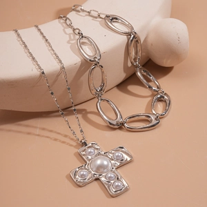 Gros plan d'un ensemble de colliers argentés à plusieurs couches avec perles et croix