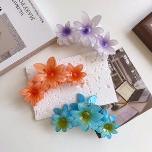 Detail of candy color flower hair claws in purple, orange, and blue resin finish
