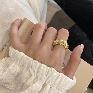 Detailed view of an adjustable gold ring with irregular lava texture worn on a finger
