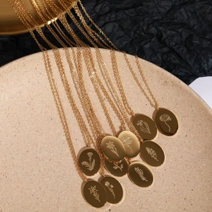 Close-up of gold stainless steel oval pendants with engraved floral patterns on ceramic