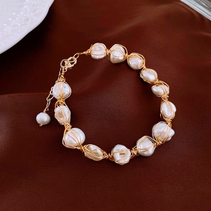 Detailed view of baroque pearls and gold-plated wire-wrapped bracelet on silk