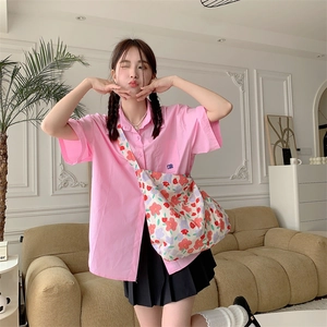 Pink short-sleeved shirt paired with black pleated skirt and floral crossbody bag