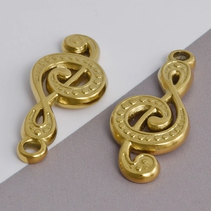 Detailed view of two gold treble clef music note pendants with textured metal finish