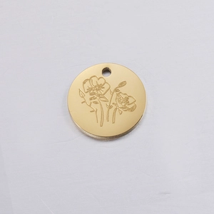 Close-up of a gold round metal pendant featuring an intricate engraved birthday flower pattern