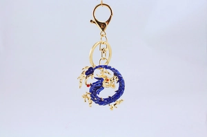 Detailed view of blue dragon metal keychain with premium gold finish hardware on white