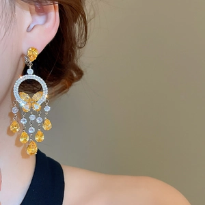 Detail of butterfly drop earrings with yellow teardrop stones on a side-view model