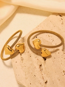 Detail of 18K gold mesh woven bracelets with heart-shaped pendants on silk background