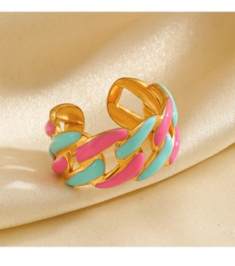 Macro view of gold chain ring with pink and cyan enamel detailing on satin background