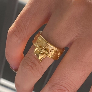 Gold-plated wide band heart ring with embossed pattern and dangling heart charm
