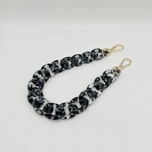 Macro shot of acrylic resin chain strap with black and white marble pattern and gold clasps
