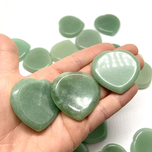 Macro detail of three polished green heart-shaped adventurine worry stones held in hand