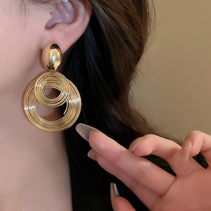 Close-up of gold geometric layered earrings with coiled wire circles on model