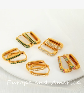 Close-up of geometric gold-plated earrings set with colorful zircon and secure clasp