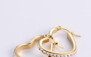 Close-up of golden heart hoop earrings with sparkling crystal-inlaid outer edges