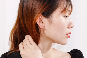 Macro detail of rose gold beaded hoop earrings featuring fine textured metal craftsmanship