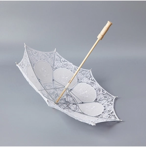Close-up of elegant white lace bridal umbrella with wooden handle for wedding decor