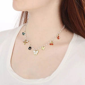 Elegant gold butterfly and pearl necklace with cherry and bee charms on a female model
