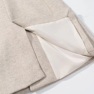 Detail of light beige wool coat hem showing thick fabric texture and smooth white lining