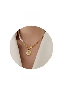 Gros plan d'un collier pendentif pièce vintage avec perles blanches et chaîne dorée
