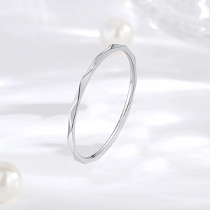 Macro detail of a 1mm thin faceted silver ring with elegant rhombic geometric texture.
