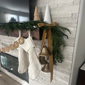 Close-up of white knit Christmas stockings and golden bells on a festive pine mantel