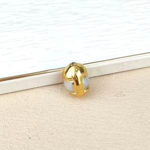 Macro shot of an irregular natural pearl pendant with a gold plated metal edge detail