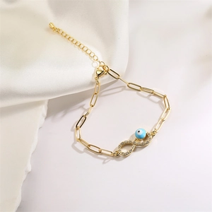 Detail of gold infinity bracelet with evil eye bead and sparkling crystal accents