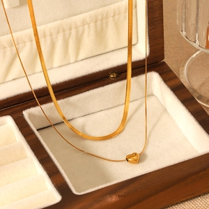 Gros plan du collier double couche doré à maille serpent avec pendentif cœur en boîte à bijoux