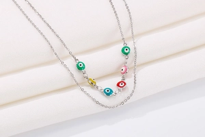 Detail of layered silver evil eye necklace with colorful enamel charms on silk