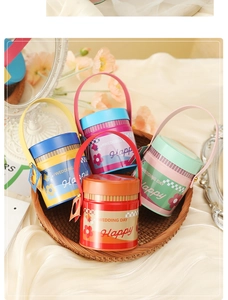Detail of round tin gift boxes with handles in colorful floral Happy Wedding designs