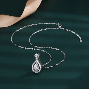 Macro detail of pear-shaped 2ct zircon pendant necklace with pavé halo on green silk