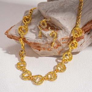 Golden snake jewelry set with sparkling rhinestones and red gemstones on a stone base