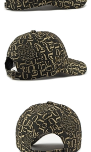 Detail view of adjustable metal buckle on black baseball cap with golden monogram pattern
