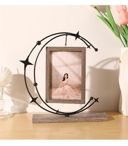 Detail of moon-shaped metal photo frame with star accents and solid wood base