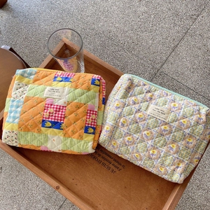 Detailed close-up of soft quilted floral makeup bags in orange plaid and purple patterns