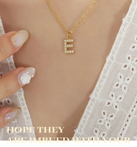Macro shot of gold letter E pendant with crystal inlay on a delicate chain necklace