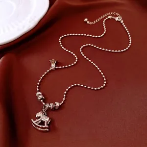 Collier cheval à bascule en or rose avec cristaux blancs sur fond de satin luxueux