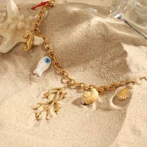 Goldene Edelstahlkette mit Meeresanhängern wie Seepferdchen und Muscheln am Strand