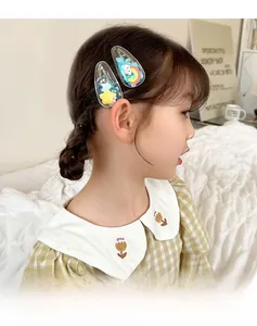 Detail of girls' hair clips with rainbow, star, and glitter motifs on a young model