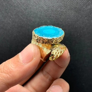 Detalle de anillo de cóctel con gran cristal azul y banda ancha martillada de oro de 14K
