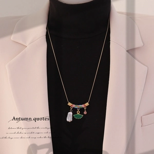 Retro gold necklace with colorful enamel heart, baroque pearl, and gems on a model
